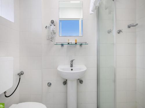 a white bathroom with a sink and a shower at Boat Harbour Motel in Wollongong