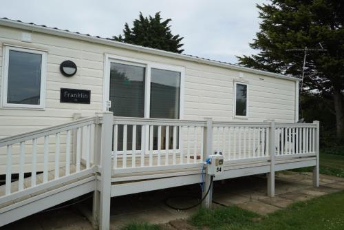 a white and blue house with a wooden deck at Heacham Gold Caravan in Hunstanton