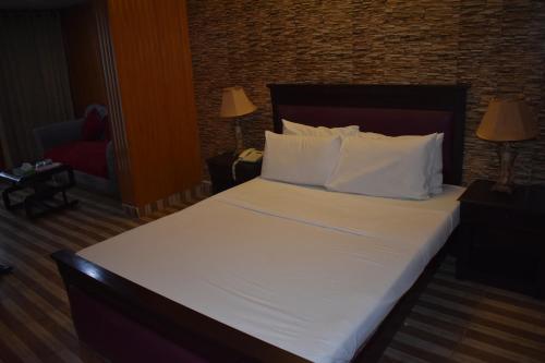 a bedroom with a large bed with white sheets and pillows at Elysium 99 in Islamabad