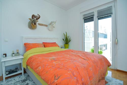 um quarto com uma cama com um edredão laranja e uma janela em Athens Stylish top floor apartment Syntagma metro em Atenas