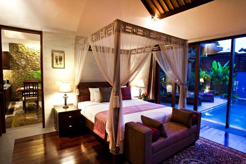 a bedroom with a canopy bed and a couch and a patio at Gending Kedis Luxury Villas & Spa Estate in Jimbaran