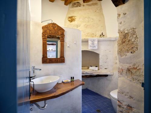 uma casa de banho com um lavatório, um espelho e um WC. em Kambos House em Kimolos