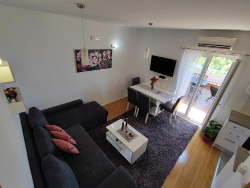 ein Wohnzimmer mit einem schwarzen Sofa und einem Schreibtisch in der Unterkunft Apartments Kola in Banići