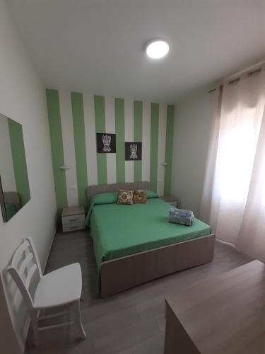 a bedroom with a green bed and a white chair at Le Camere Del Villaggio in Agrigento