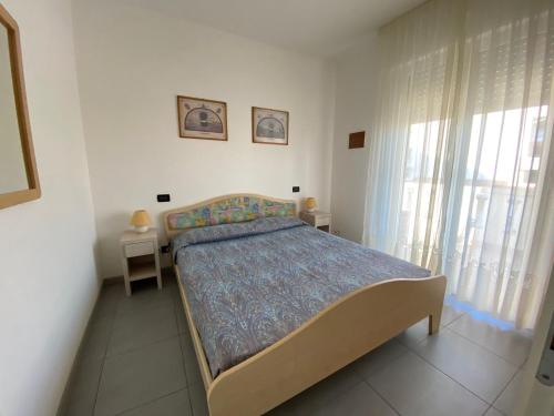 1 dormitorio con 1 cama en una habitación con ventana en Appartamenti al Cigno, en Lignano Sabbiadoro