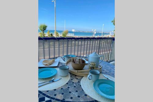 une table avec des assiettes et des ustensiles bleus sur un balcon dans l'établissement La cabine de Léontine, à La Baule