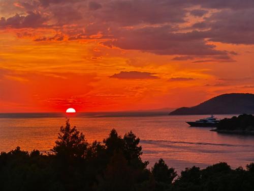 a sunset over the ocean with a boat in the water at Jees Exclusive Apartments Hvar in Stari Grad