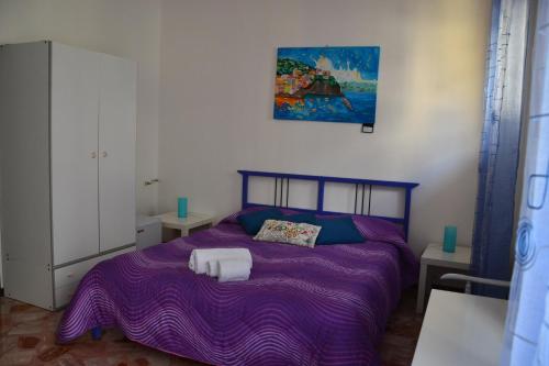 エーリチェにあるA Due Passi da Erice B&Bのベッドルーム1室(紫色のベッド1台付)が備わります。壁に絵画が飾られています。
