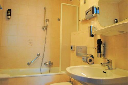 y baño con ducha, aseo y lavamanos. en Hotel Continental Koblenz en Coblenza