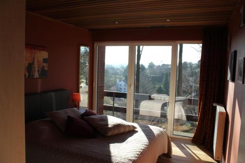 a bedroom with a bed and a large window at Green Hill Apartment Overijse in Overijse