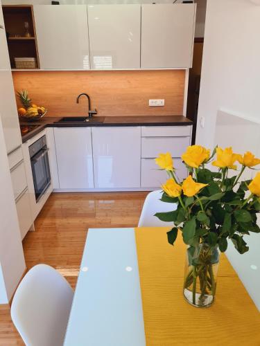a kitchen with a table and yellow flowers in a vase at Juliana Apartment Bohinj Lake in Bohinj