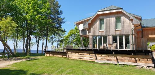 ein Holzhaus mit einer Veranda auf einem Rasen in der Unterkunft Guest House Vidlauči in Skulte