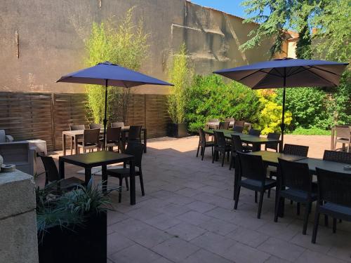 a patio with tables and chairs with umbrellas at Hôtel du Beffroi Gravelines Dunkerque in Gravelines