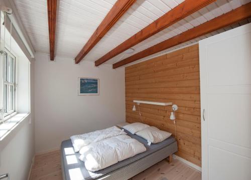 a bed in a room with a wooden wall at Hovborg Ferieby - Torpet 81 in Hovborg