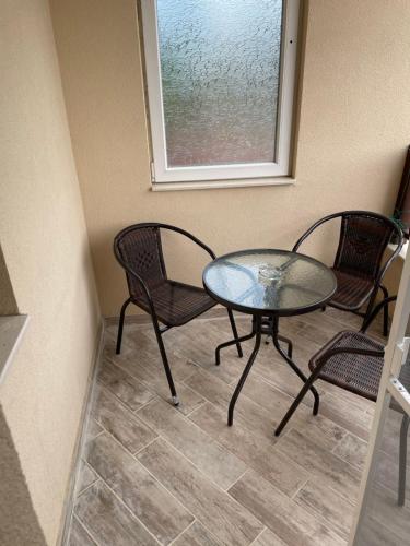 a glass table and two chairs and a window at Family Hotel Malibu in Chernomorets