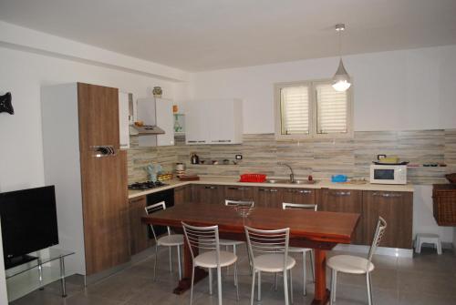 a kitchen with a wooden table and chairs in it at Summer Beach Rooms in Fontane Bianche