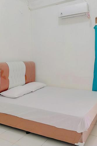 łóżko w pokoju z białą ścianą w obiekcie AA BUNGSU Syariah Balekambang Ciletuh Sukabumi RedPartner w mieście Cilowa