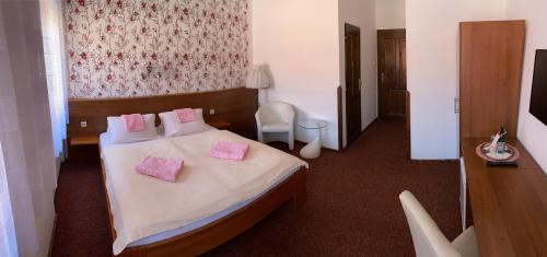 a bedroom with a bed with pink pillows on it at Pension Falko in Český Krumlov