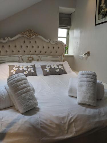 a white bed with pillows and towels on it at Pinfold Holiday Cottage in Skipton
