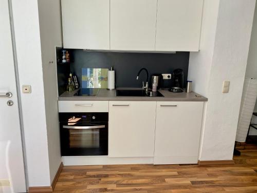 uma cozinha com armários brancos e um lavatório em Zentrale Ferienwohnung mit Balkon in Aachen em Aachen