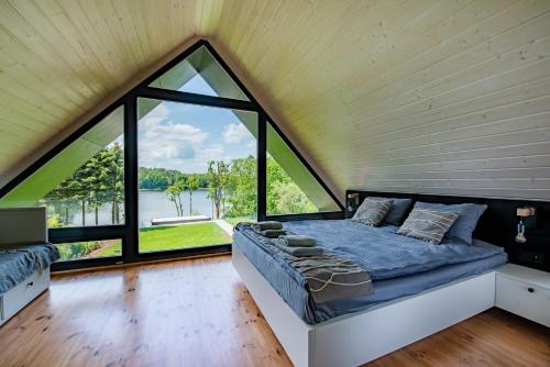 a bed in a room with a large window at NATERIA DOMEK NAD JEZIOREM in Nattern