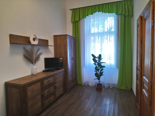 Zimmer mit einem großen Fenster und grünen Vorhängen in der Unterkunft Dolina Apartman in Eger