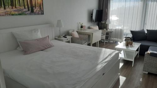 a bedroom with a white bed and a living room at Seaside Appartement 458 Vier Jahreszeiten in Hahnenklee-Bockswiese