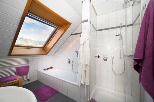 a bathroom with a tub and a shower with a window at Ferienwohnung Mara in Öhningen