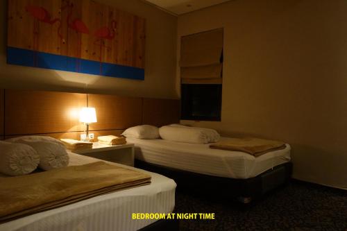 a hotel room with two beds and a lamp at Vimala Hills Resort Cozy Villa Puncak Gadog Bogor in Bogor