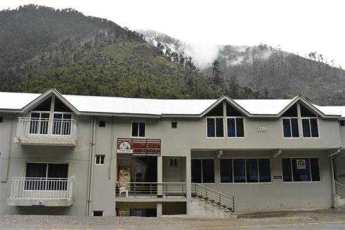 a large white building with a mountain in the background at Cedar Vista Resort in Kāgān