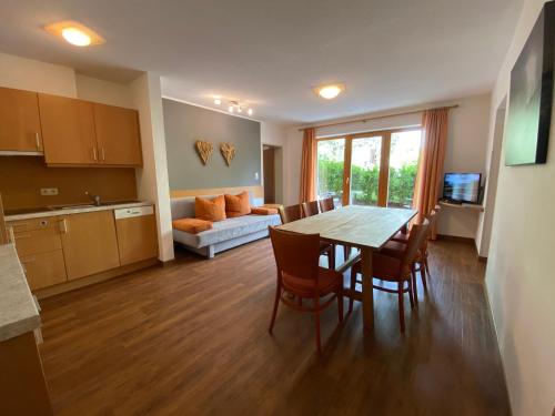 Apart Hotel Neier في لاديس: مطبخ وغرفة معيشة مع طاولة وكراسي
