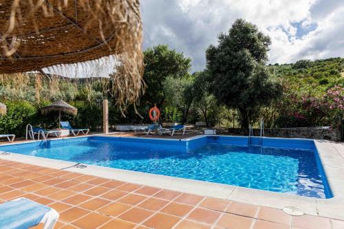 a large swimming pool in a yard with a patio at El Horcajo in Montecorto