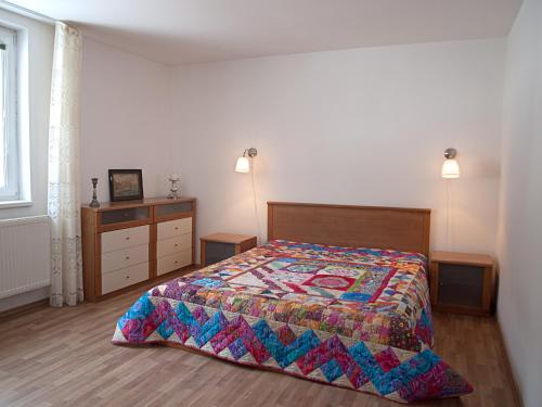 a bedroom with a bed with a colorful quilt on it at Penzion Malina in Hronská Dúbrava