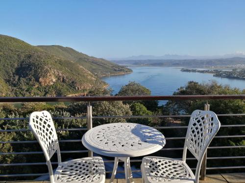 a table and chairs on a balcony with a view of a river at Knysna Pearl View Guest House in Knysna