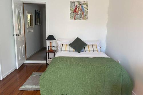 a bedroom with a bed with a green blanket at Cozy self-contained unit surrounded by nature in Goonellabah
