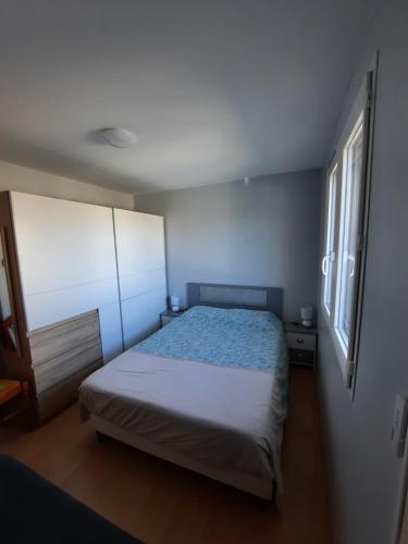 une petite chambre avec un lit et deux fenêtres dans l'établissement Chalet de Certe, à Audenge