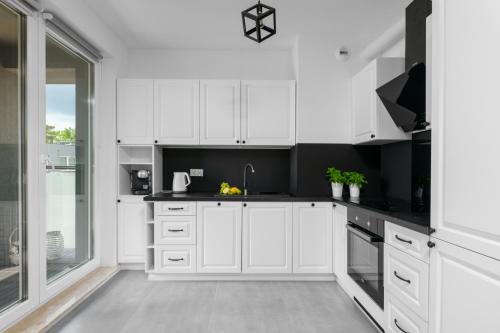 a kitchen with white cabinets and black counter tops at Otwock PREMIUM Apartment- CENTRUM PKP in Otwock
