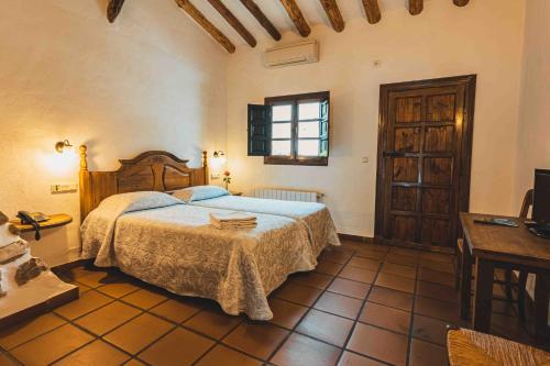 a bedroom with a bed and a table and a window at Hotel Rural El Horcajo de Ronda in Montecorto