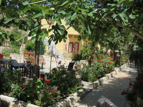 a garden in front of a yellow building with flowers at Villa Costas - Popi in Sívas
