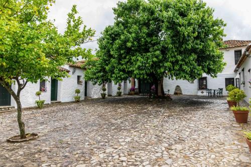 a stone driveway in front of a white house with trees at Hotel Rural El Horcajo de Ronda in Montecorto