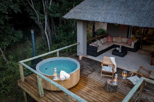 a jacuzzi tub on a wooden deck with a couch at Rukiya Safari Camp in Hoedspruit