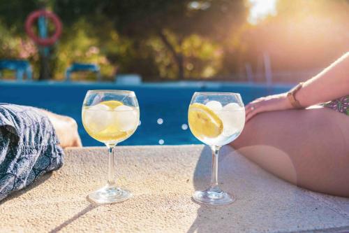 two wine glasses sitting on a table next to a woman at Hotel Rural El Horcajo de Ronda in Montecorto