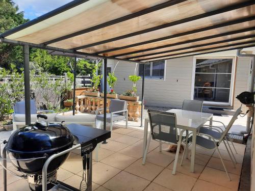 a patio with a grill and a table and chairs at Chalet de Certe in Audenge