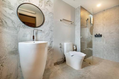 La salle de bains est pourvue d'un lavabo, de toilettes et d'un miroir. dans l'établissement PLAAI Plus Hotel Rayong, à Rayong