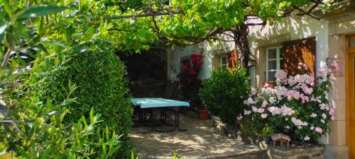 a garden with a table and flowers on the side of a house at L'Art des Choix in Saint-Jean-de-Pourcharesse