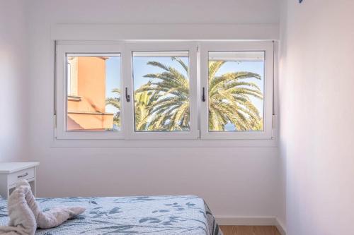 1 dormitorio con ventana y palmera en Apartamento con vistas al mar en Fisterra, en Finisterre