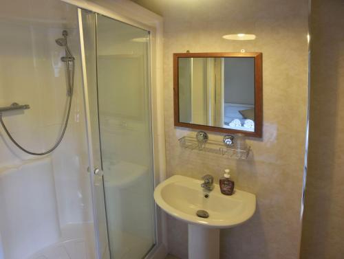 y baño con lavabo y ducha con espejo. en The Village Bed and Breakfast en Cushendall