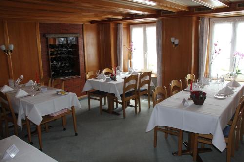un comedor con mesas y sillas blancas y ventanas en Hotel Restaurant Rössli, en Schönenberg
