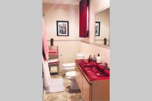 uma casa de banho com um lavatório vermelho e um WC. em La casa de Aneta em Barbastro