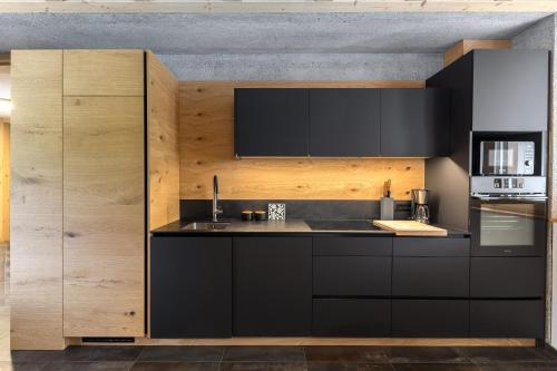 a kitchen with a black counter and wooden walls at Hiša Križaj in Bohinj